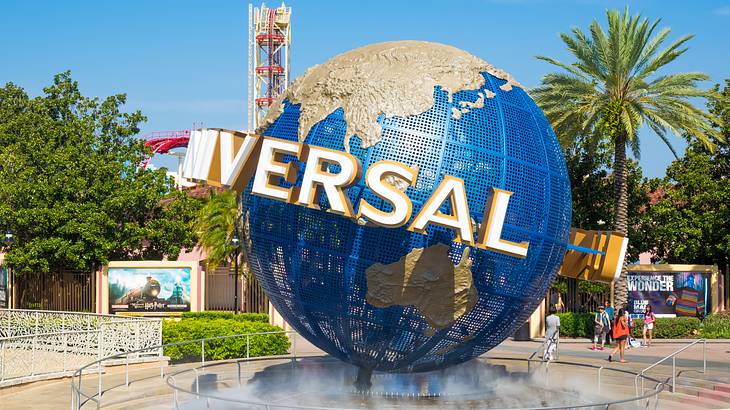 Universal iconic globe with people walking at the back and surrounded by trees