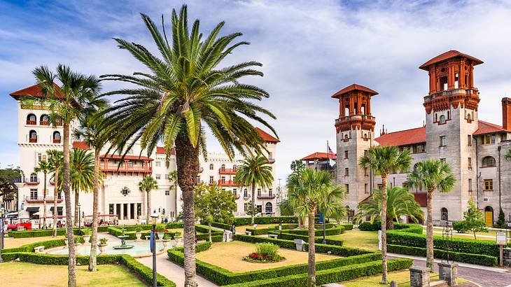 Spanish colonial buildings next to a green garden and palm trees