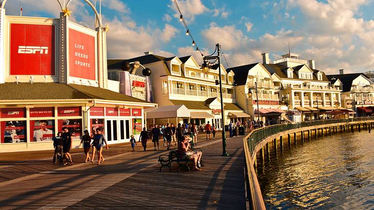 People walking on a wooden promenade with boutique stores overlooking a lake