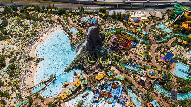 Aerial shot of a brightly-colored waterpark with slides and people swimming in pools