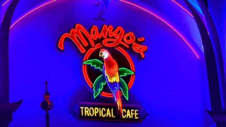 A bright neon sign with a parrot that says "Mango's Tropical Cafe"