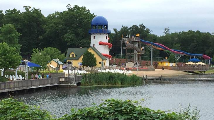 A lake surrounded by a park with rides, some houses, and green trees