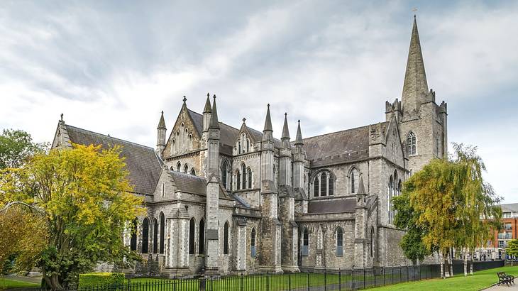 The striking but sombre architecture of a cathedral surrounded by green trees The striking but sombre architecture of a cathedral surrounded by green trees