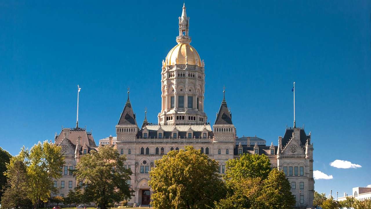 A state capitol building with Gothic architecture and a golden dome under a clear sky