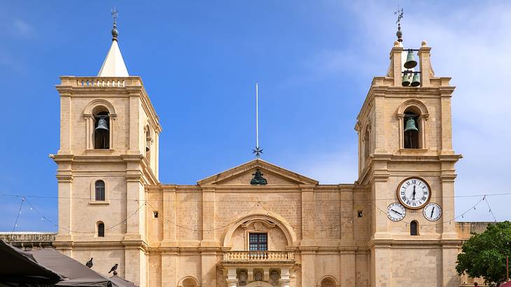 The exterior of a beige-coloured church with two towers against a blue sky The exterior of a beige-coloured church with two towers against a blue sky