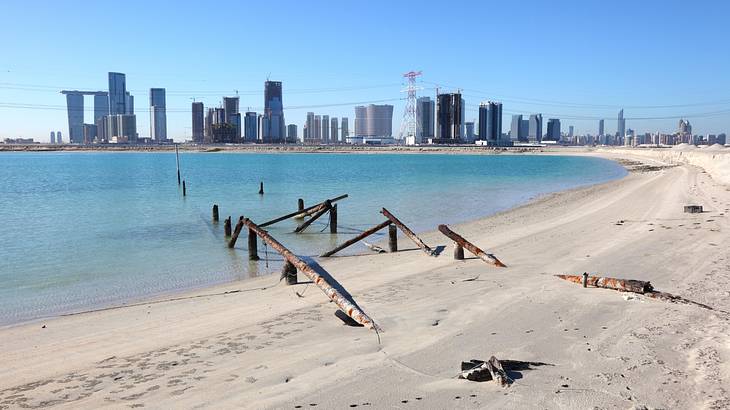 A city skyline full of tall buildings from a sandy beach with blue water