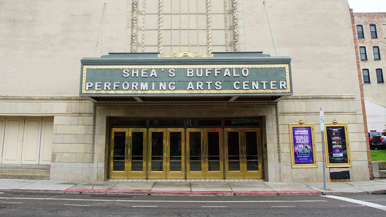 A stone building with gold doors and a "Shea's Performing Arts Center" sign