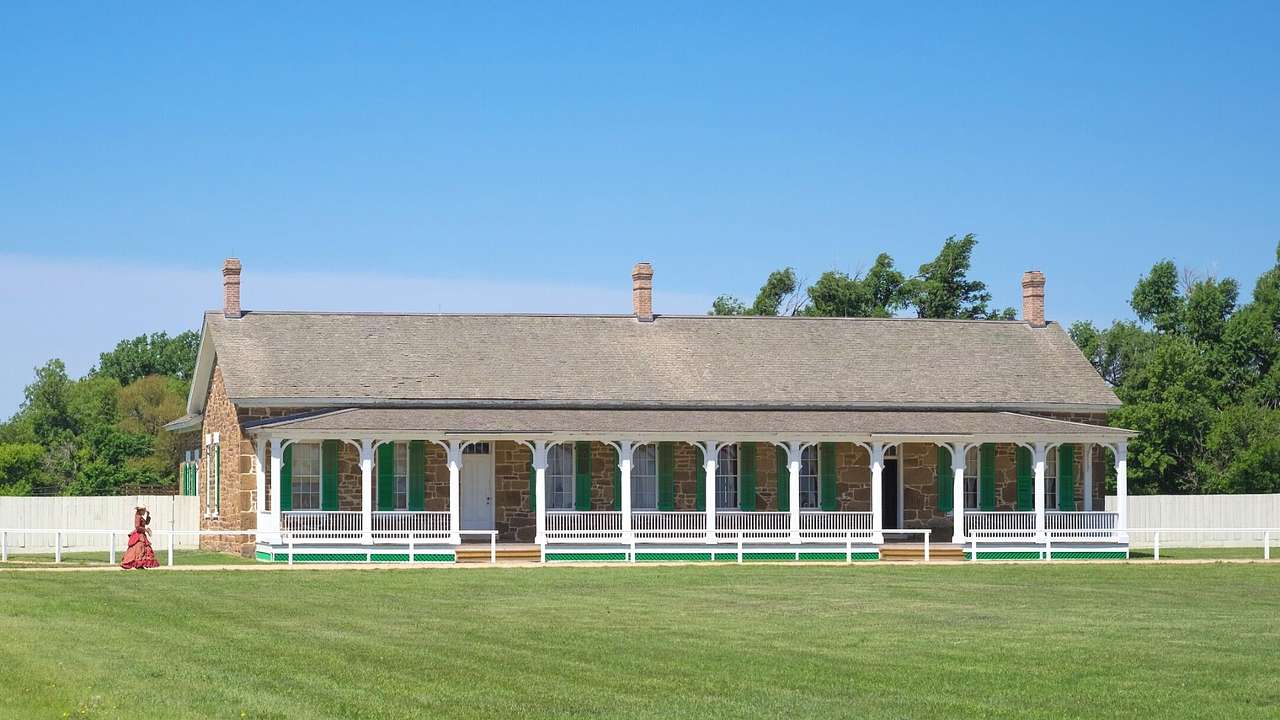 A rectangular building with white posts and a green lawn in front of it
