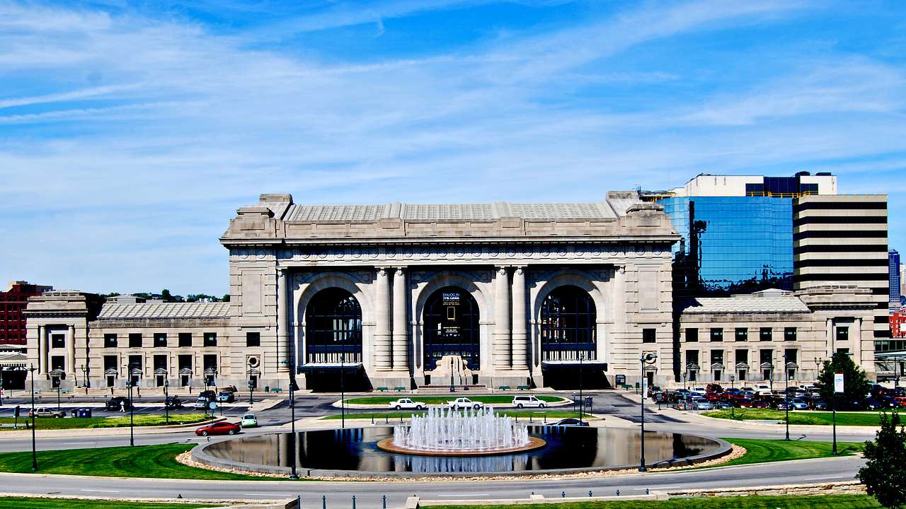 A large concrete building with a fountain in the foreground under a blue sky