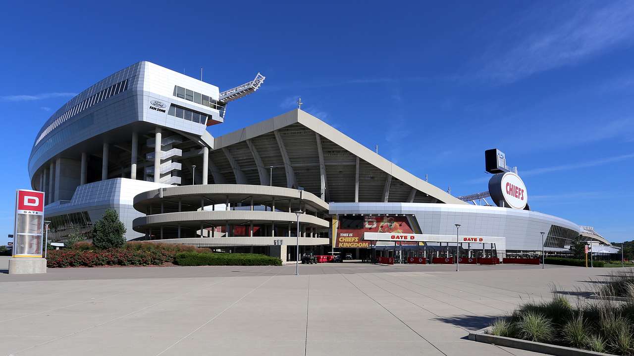 A modernist-style stadium with an empty parking lot in front
