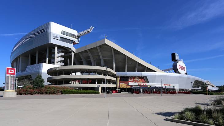 A modernist-style stadium with an empty parking lot in front