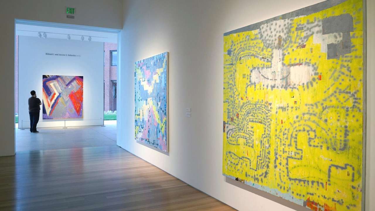A hall in an art gallery with three colorful paintings on display