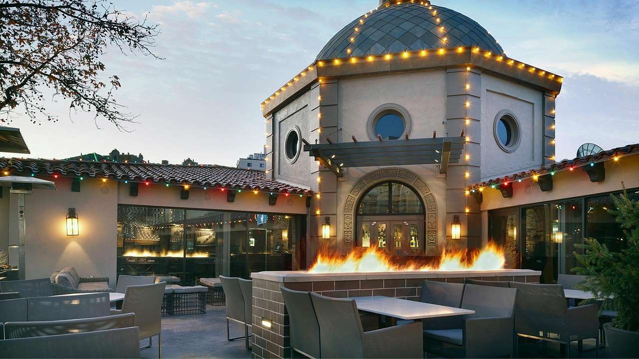 An outdoor patio with fire pits and a building behind it with a domed roof