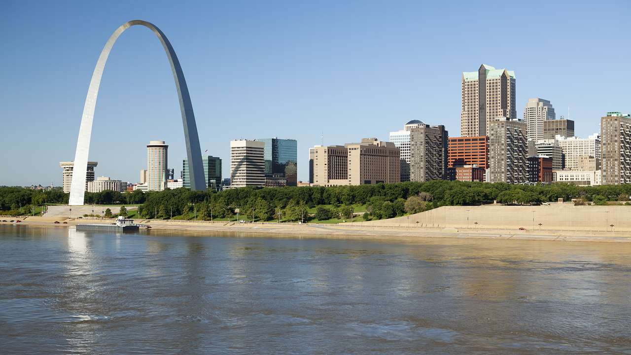 Tall skyscrapers and an arch near a body of water