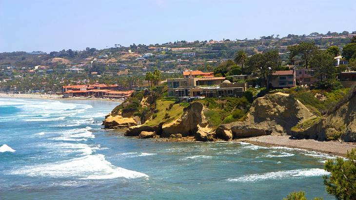 The ocean next to greenery-covered hills with houses on them