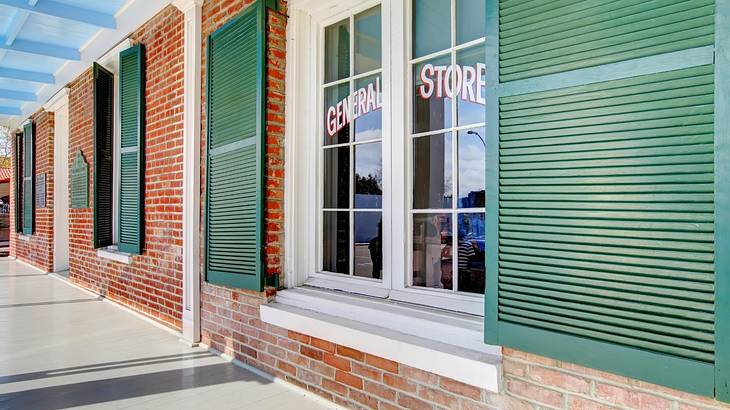 A red brick building with green window shutters and a "General Store" sign