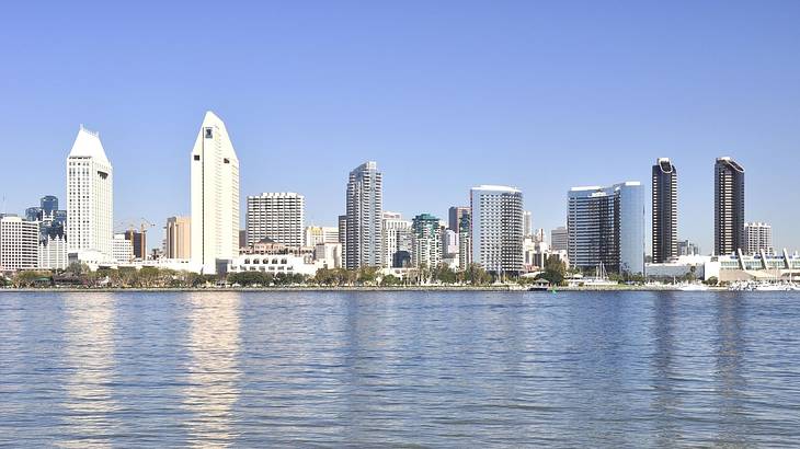 A city skyline with water in front of it under a blue sky