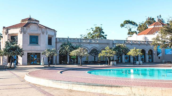 A stone building with arches next to a courtyard with a fountain