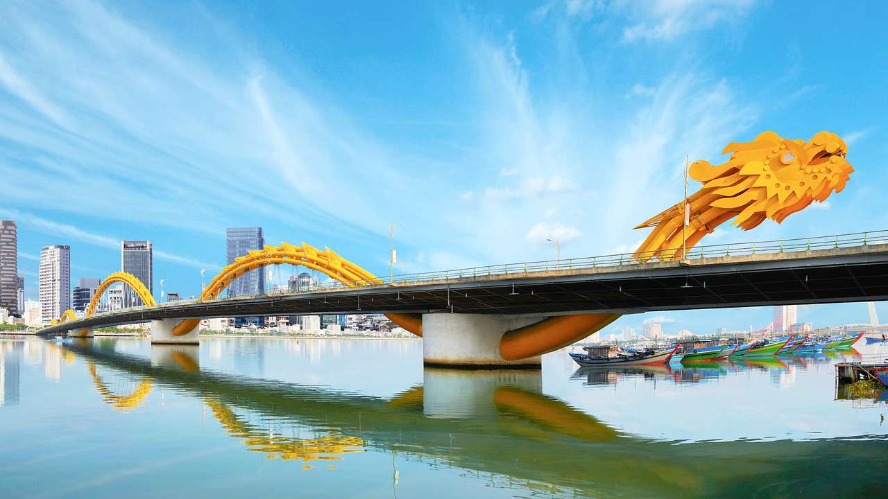 A bridge designed with a long golden-yellow dragon with water below