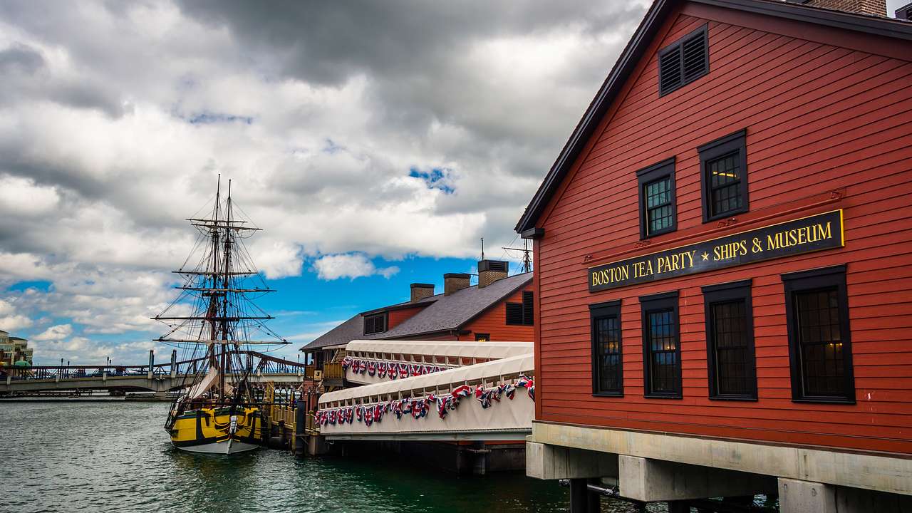 A boat docked at a pier with a red building titled "Boston Tea Party Ships - Museum"