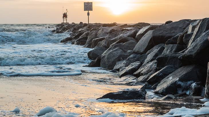 A beach with waves crashing on grey rocks at sunrise A beach with waves crashing on grey rocks at sunrise
