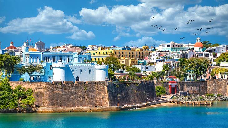 Colorful buildings on a hill with water around it under a blue sky with clouds