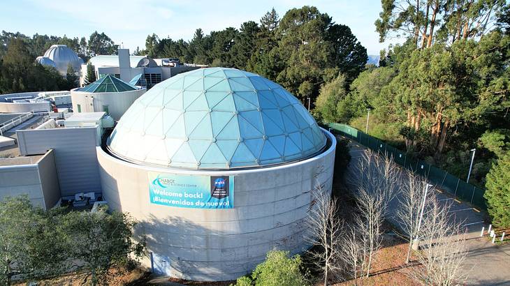 Aerial shot of a sphere-shaped structure with a dome top near trees