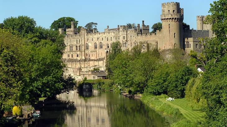 A river with trees on each side flowing towards a castle at the back
