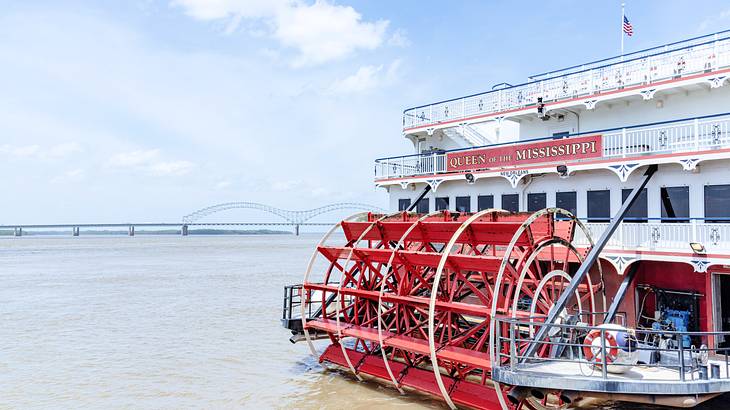A white and red riverboat with a "Queen of the Mississippi" sign on a river