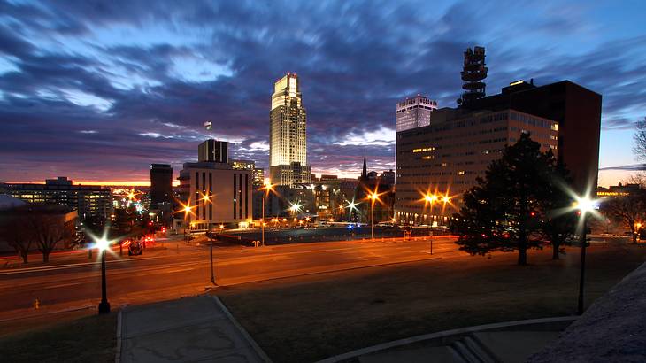 A night view of a road next to illuminated buildings and streetlights