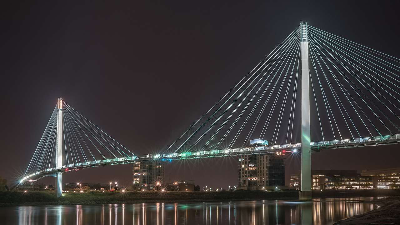 A suspension bridge over the water illuminated at night