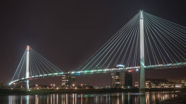 A suspension bridge over the water illuminated at night