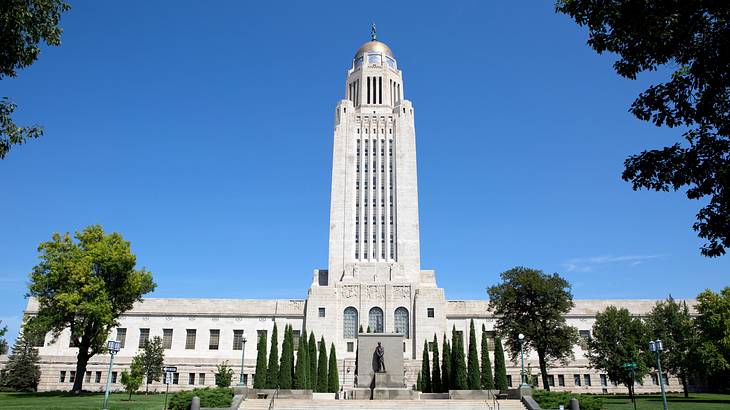 A large white building with a statue at the entrance surrounded by trees