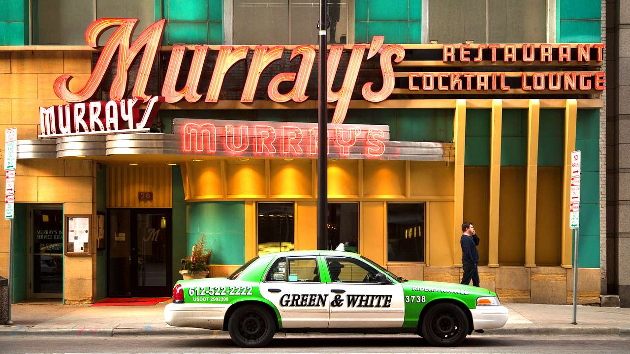 A green and white taxi parked in front of a restaurant with a red "Murray's" sign