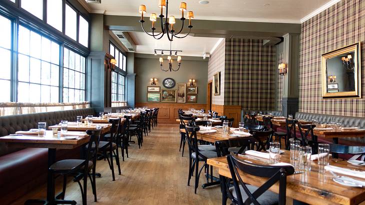 A room with windows and chandeliers and rows of tables and chairs with table settings