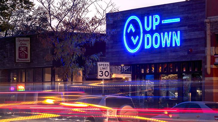 A long exposure shot at twilight of a building with a neon sign that says "Up Down"