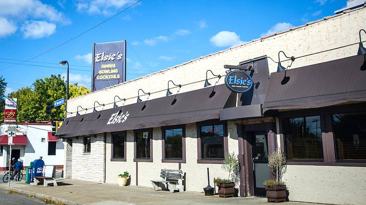 A white building with a dark blue canopy with a sign that says "Elsie's"