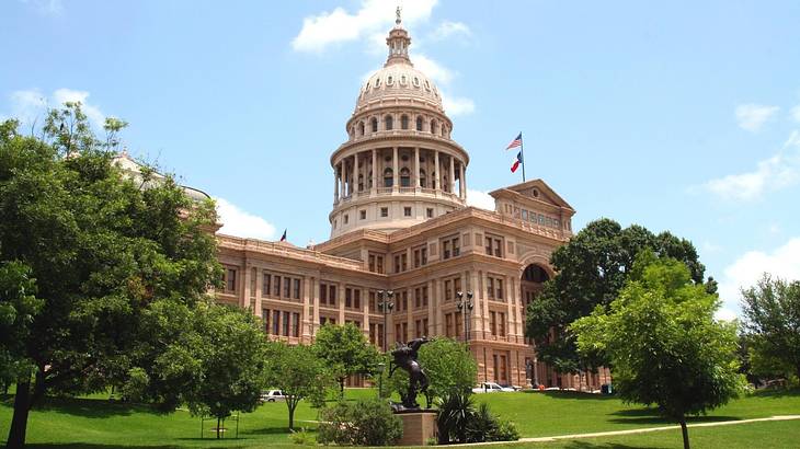 A state capitol building with a domed roof surrounded by grass and trees