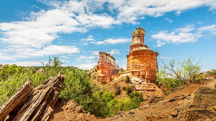 A large stone "lighthouse" structure with a few towers on a hill and some greenery