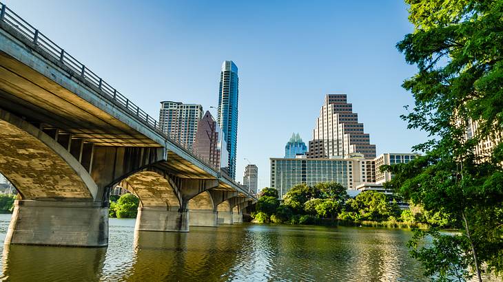 A bridge over a river with buildings and trees in the background on a nice day