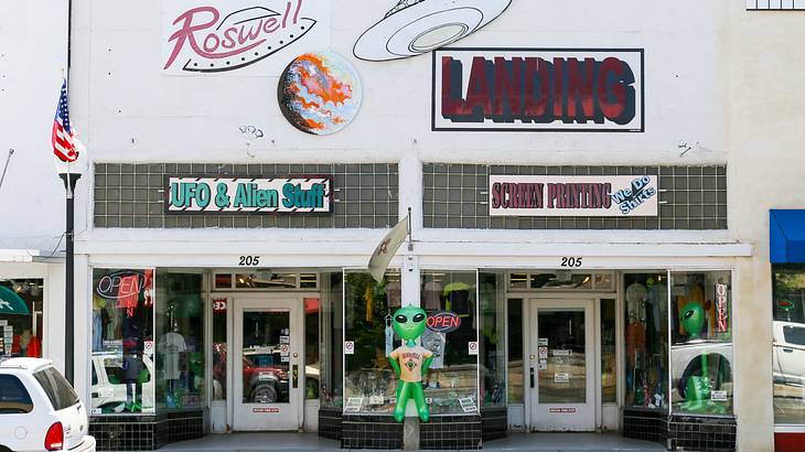 A store with a signboard of "UFO and Alien Stuff" and a green alien balloon outside