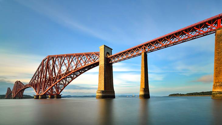 A view of a long distinctive steel structured bridge from a shore