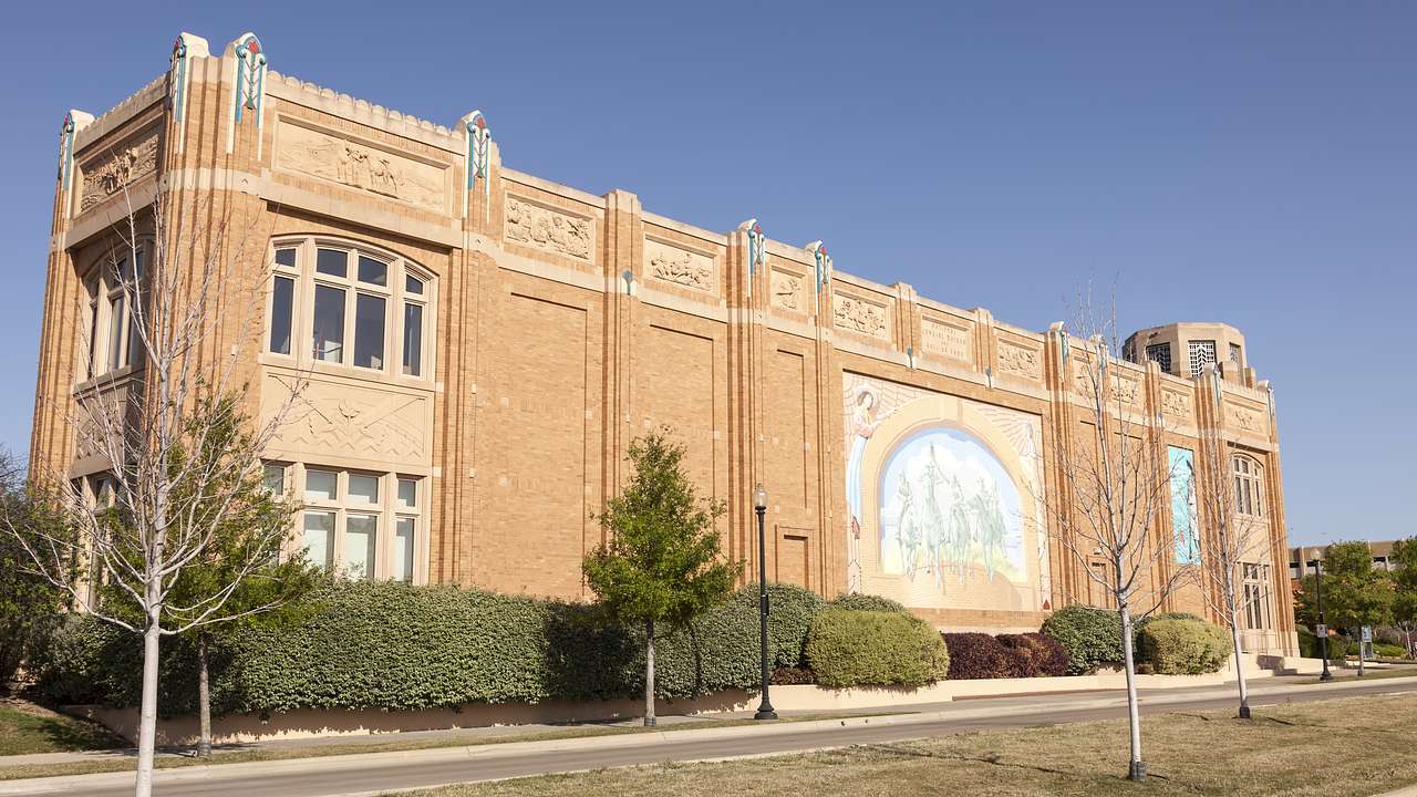 A brick building with a mural next to a street under a blue sky