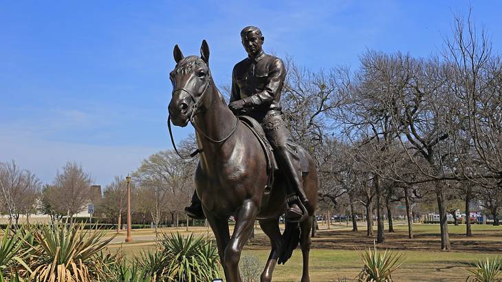 A statue of a man riding a horse in the middle of a park