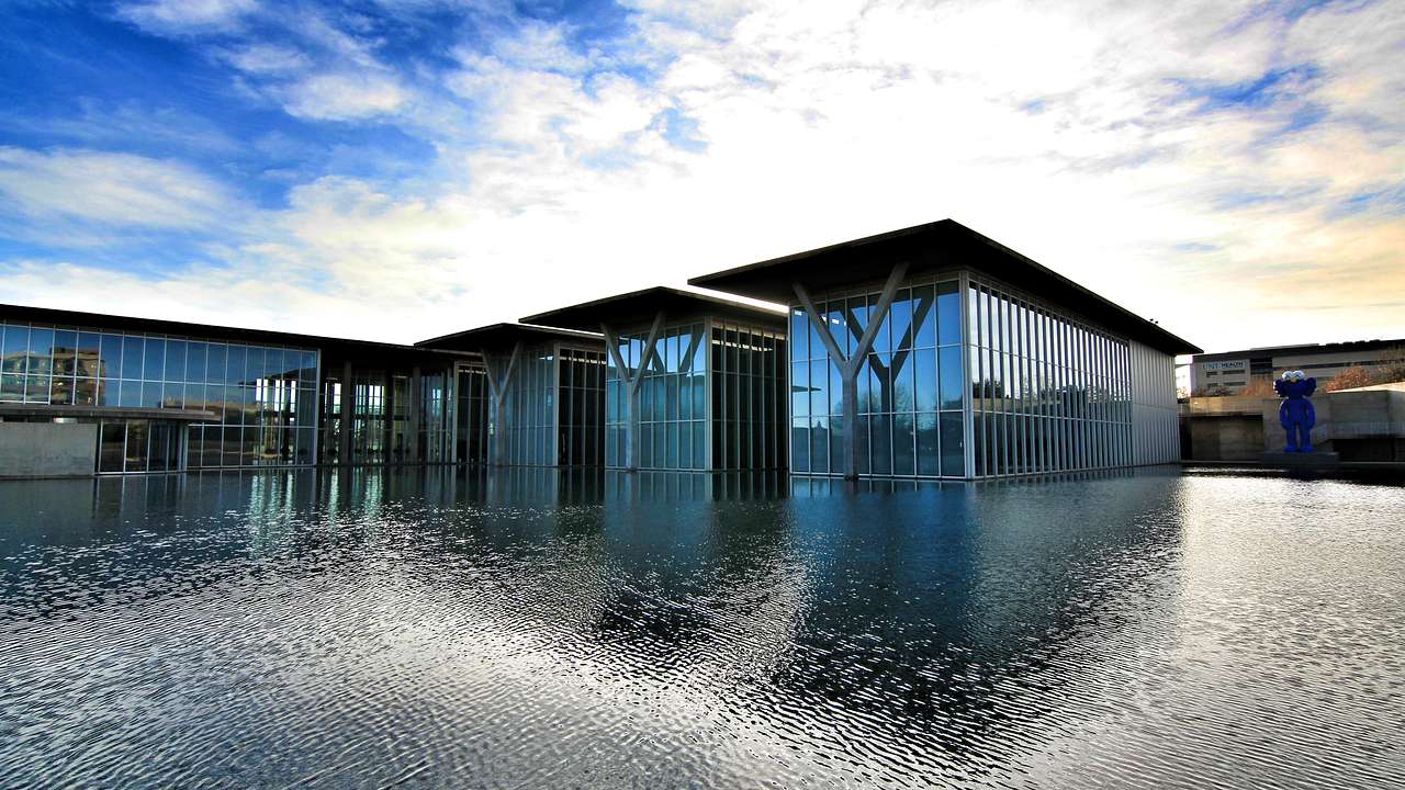 A modern building with glass panels surrounded by shallow water