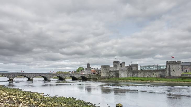 A stone bridge over a river leading to a fortified castle