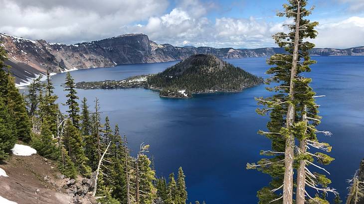 Mountains with trees surrounding a blue lake with an island in the middle Mountains with trees surrounding a blue lake with an island in the middle