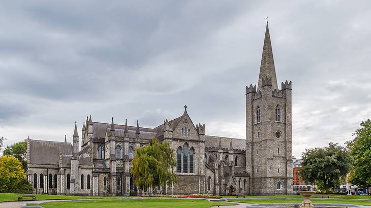 A fountain in front of a medieval cathedral surrounded by greenery