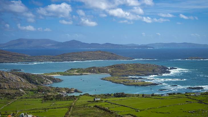 View of green islands with a mountain range and clouds at the back