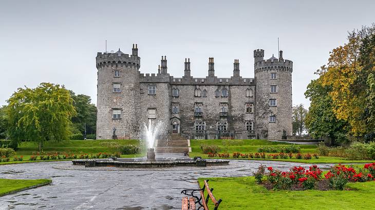 A water fountain and manicured garden in front of a medieval castle